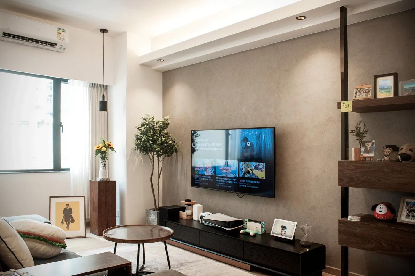 TV wall in a grey textured paint finish with a black low cabinet and timber shelving, beside a timber coffee table