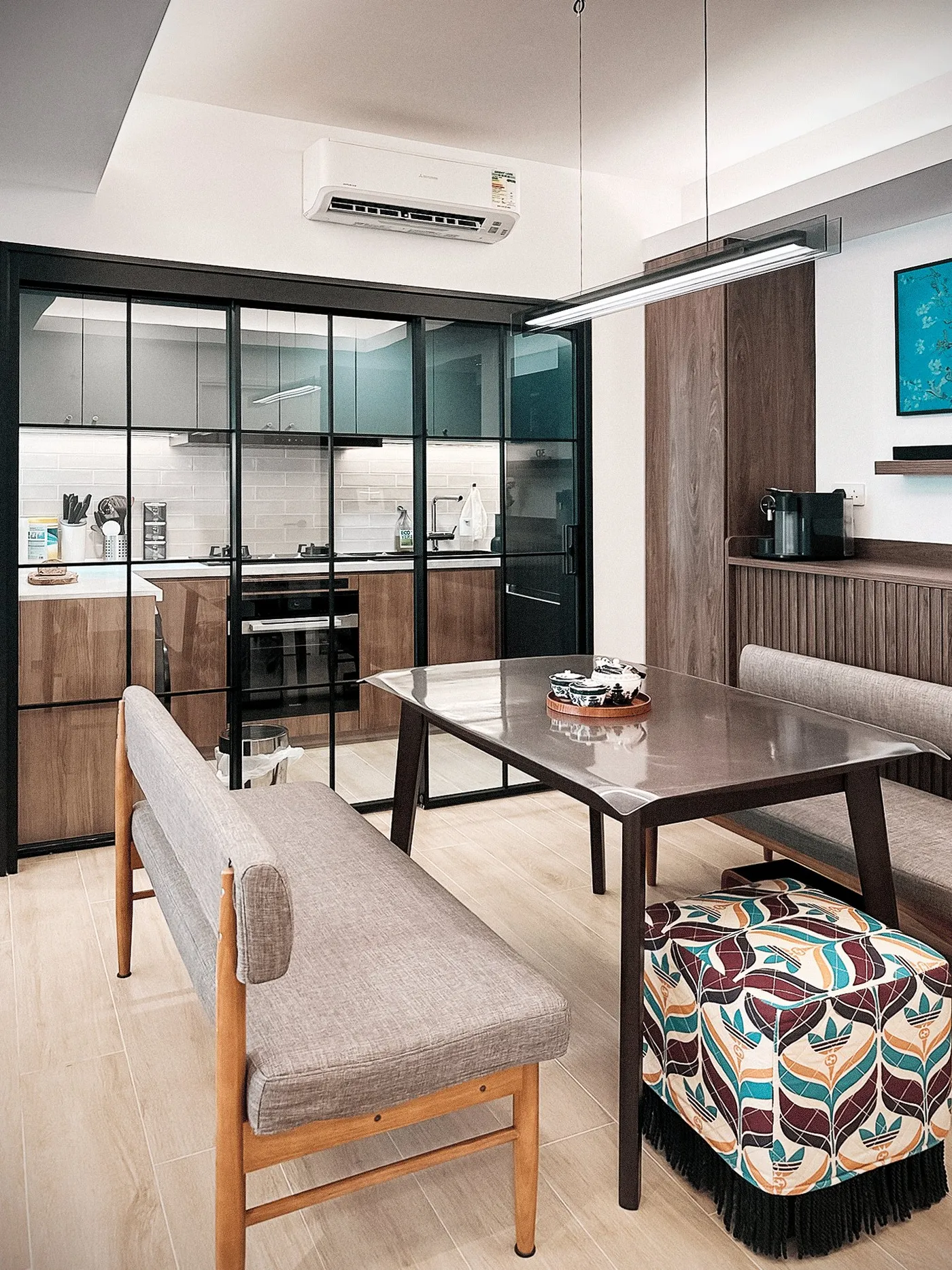 Black-framed glass door to the open kitchen, with timber base units, white wall tiles and a dark worktop