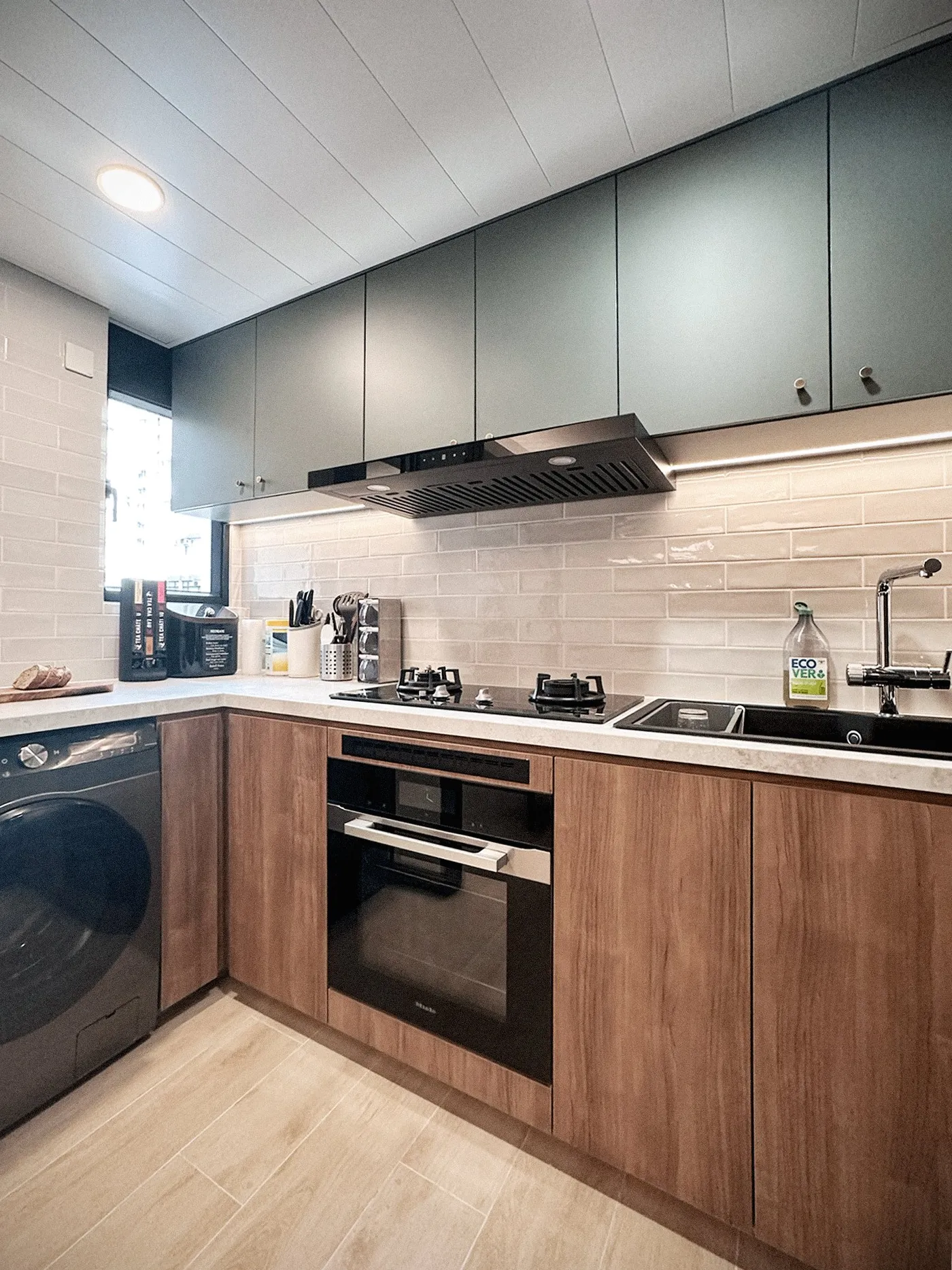 Kitchen with timber base units and grey wall cabinets, a black extractor hood, an oven and a washing machine