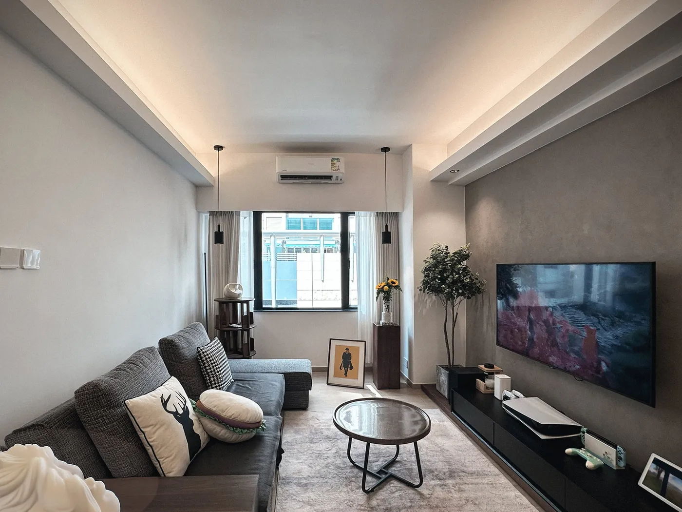 Living room with a grey fabric sofa, a round coffee table and a grey-finished TV wall