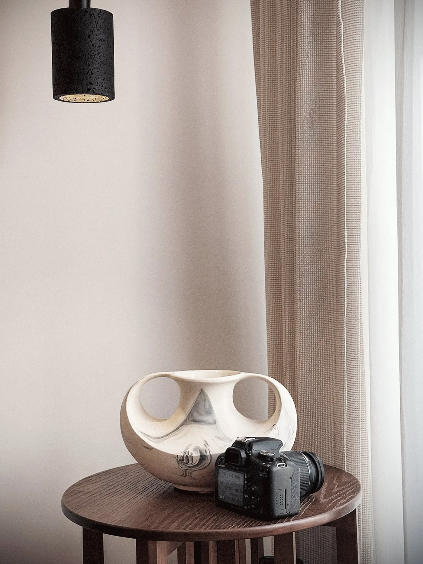 Bedroom with timber headboard shelving, a round timber side table and linen curtains