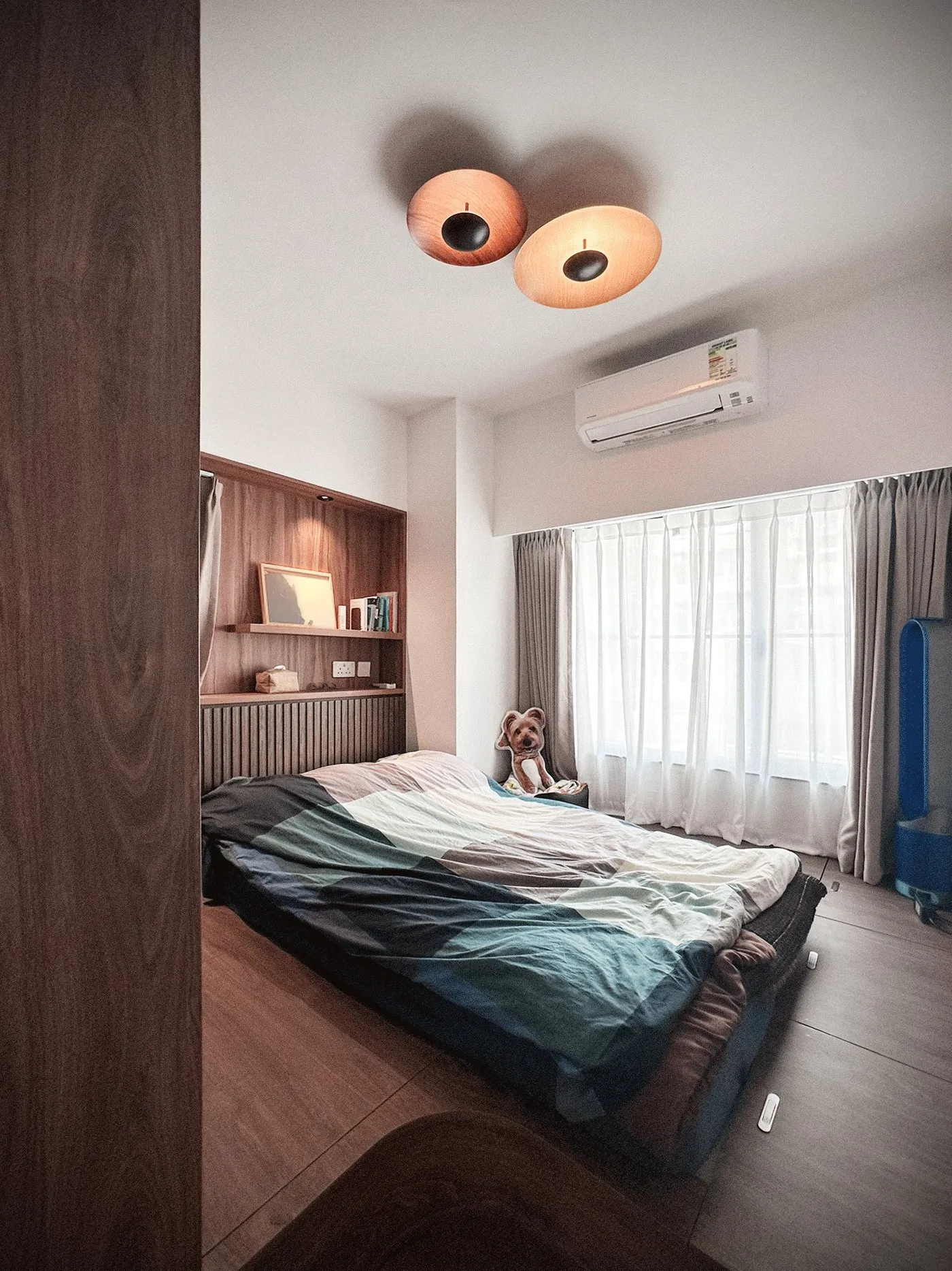 Bedroom with a timber platform bed under a round feature ceiling light, with pale curtains