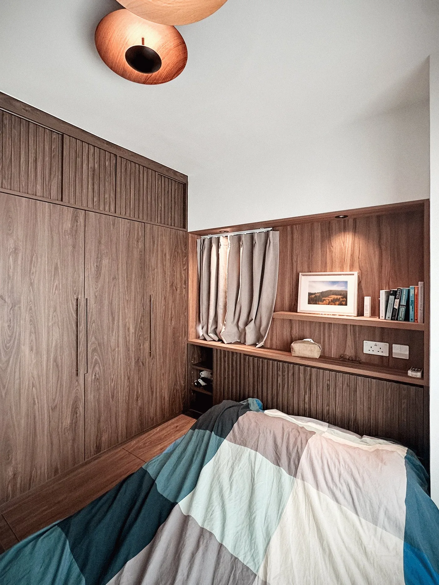 Bedroom with a built-in timber wardrobe, a colourful geometric bedspread and timber headboard shelving