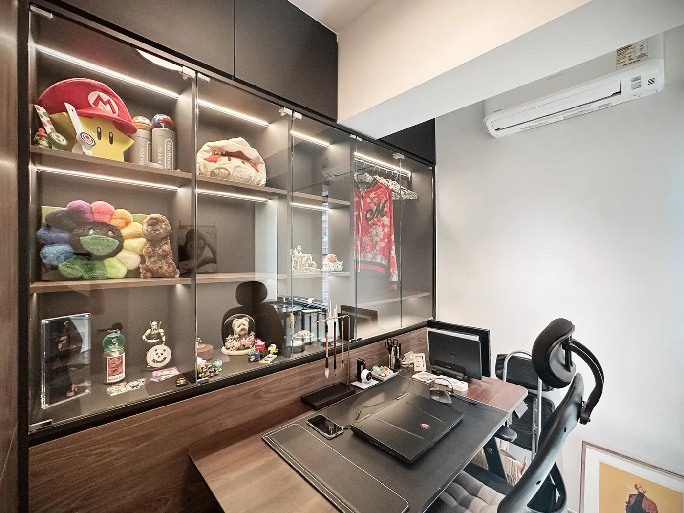 Study display cabinet in dark timber with glass doors and lit shelves holding ornaments and figures