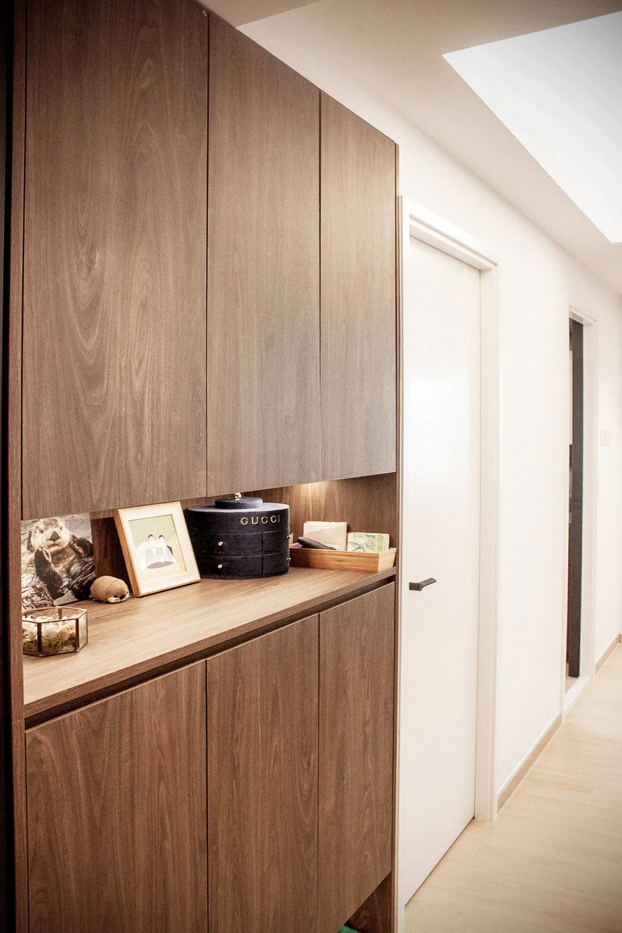 Entrance storage: a tall timber unit with an open counter holding frames and boxes