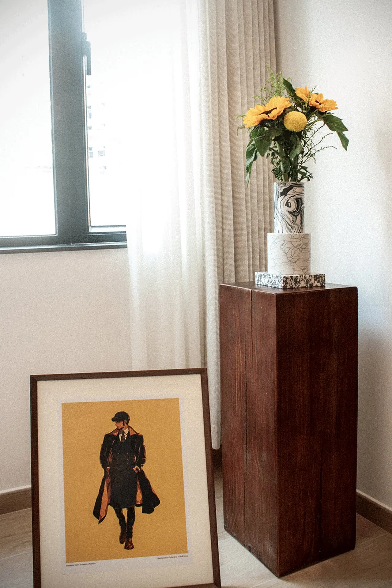 Living room window with flowers on a timber plinth and a framed portrait in front