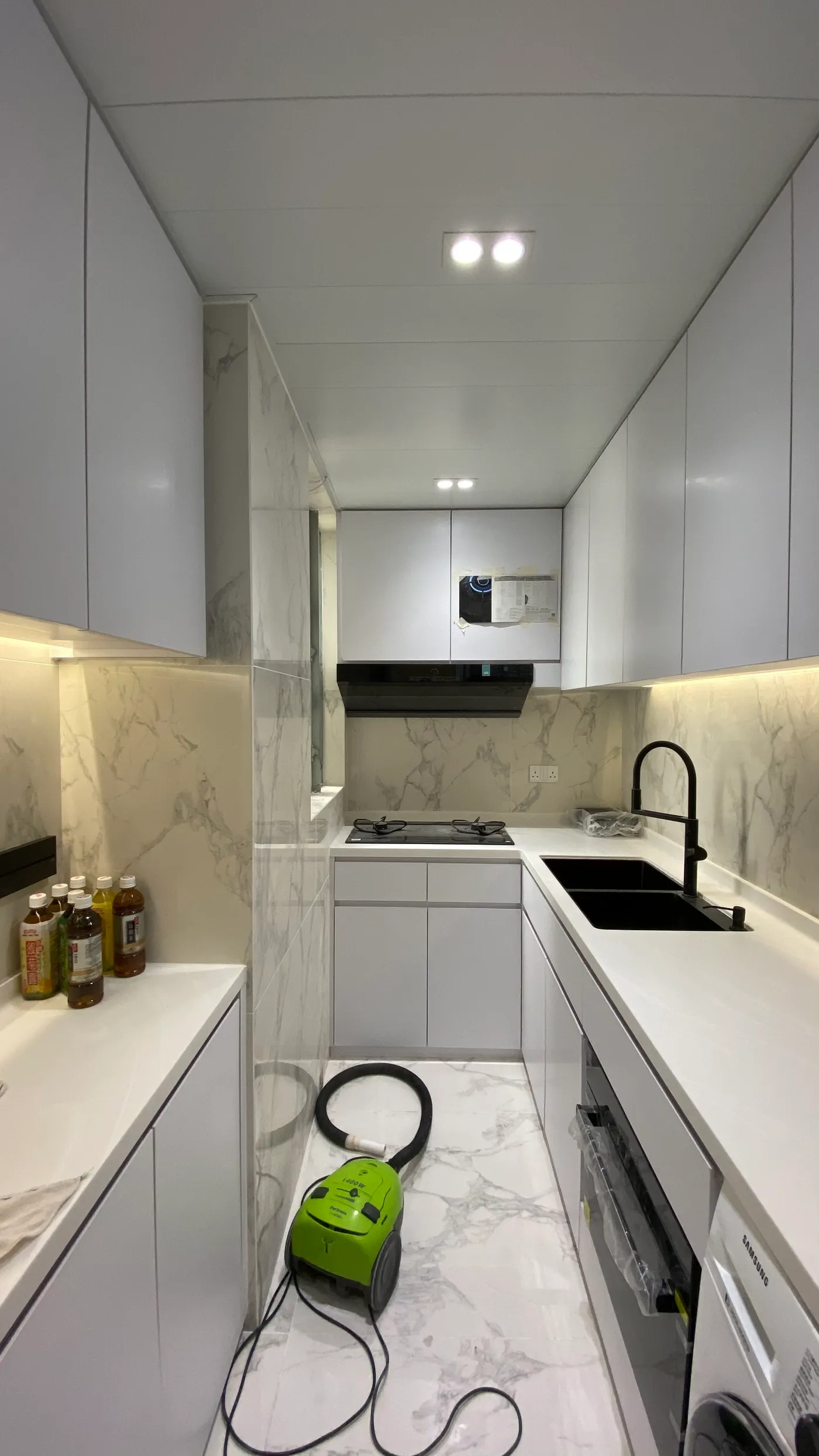 Kitchen overview with marble-veined tiled walls and black tapware and cooktop