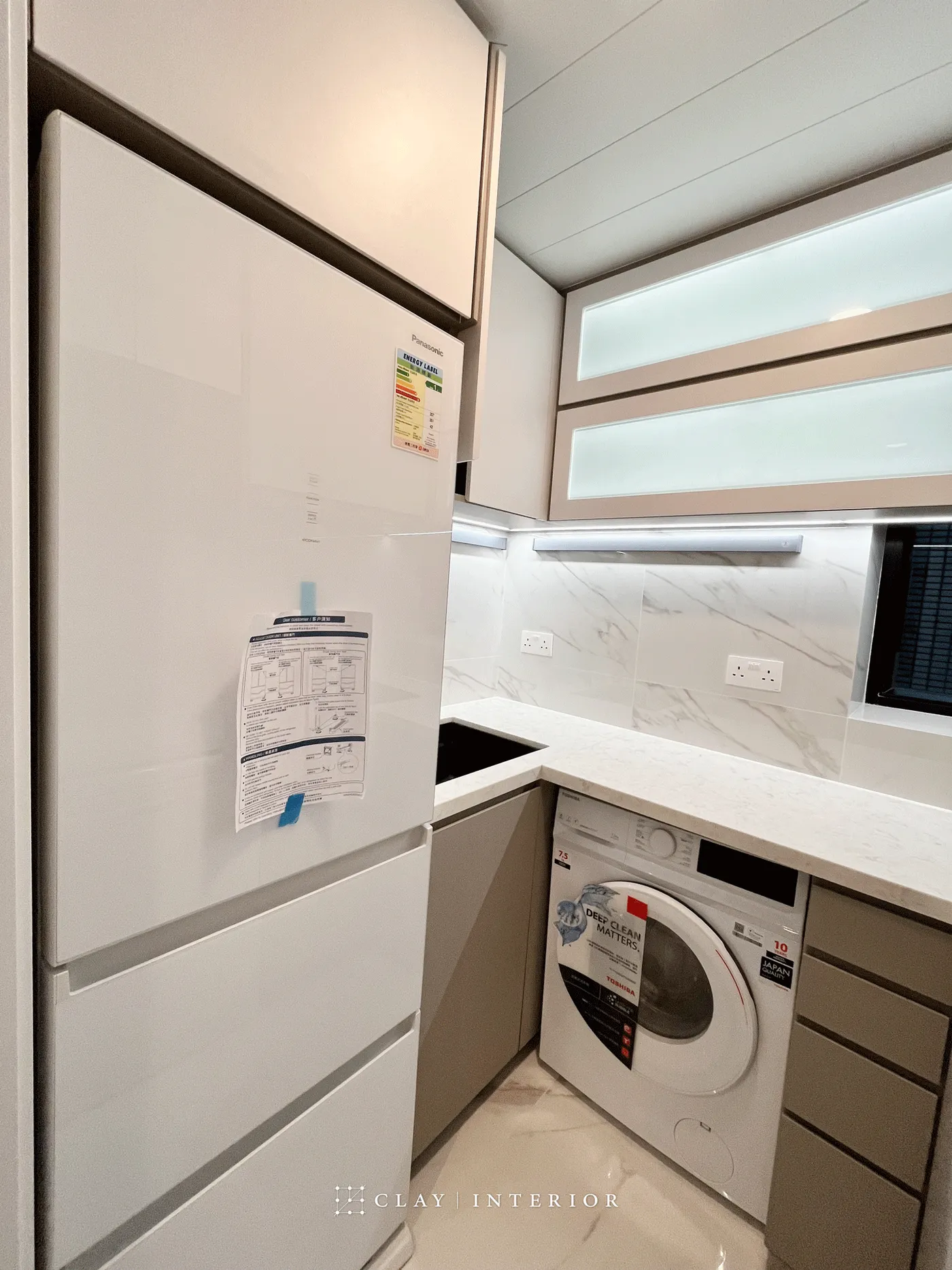 Full view of the kitchen with white marble-effect wall tiles and built-in washing machine