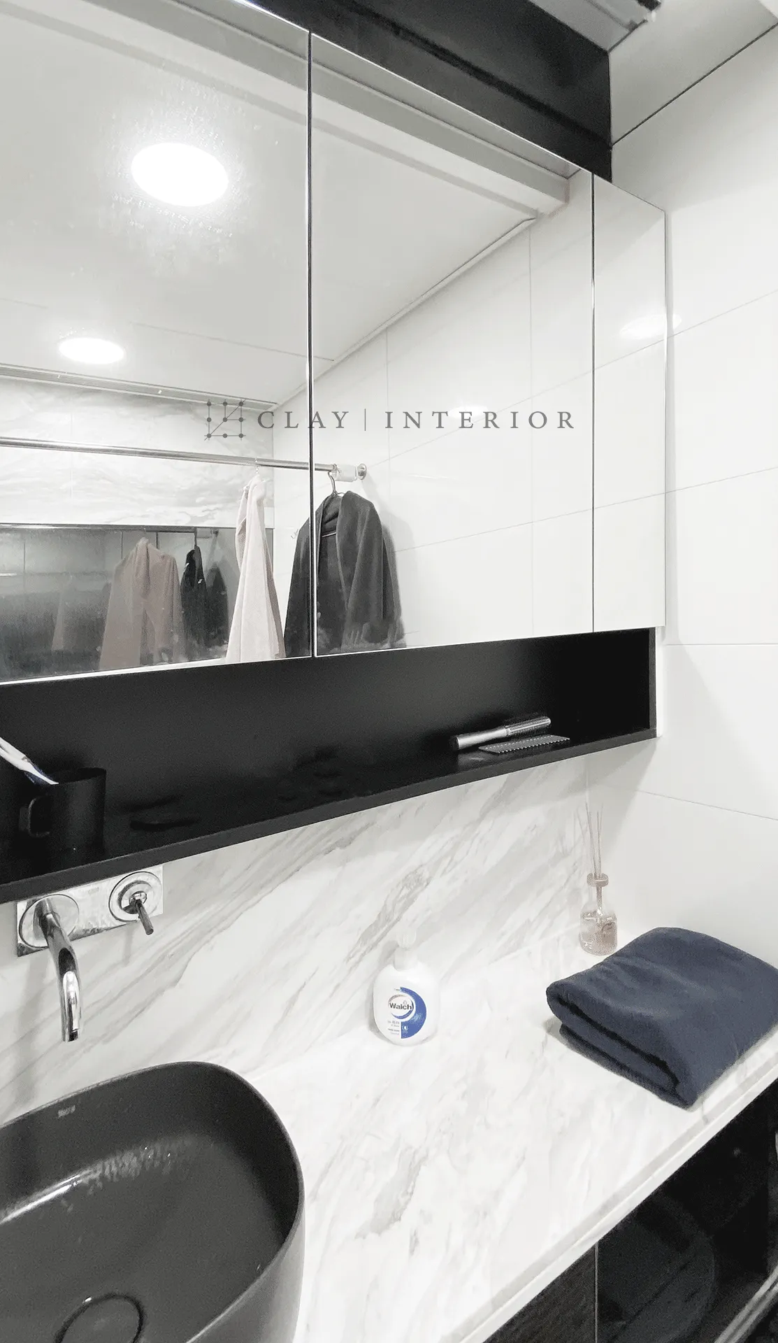 Bathroom washbasin and mirror cabinet, marble-look walls with black fittings