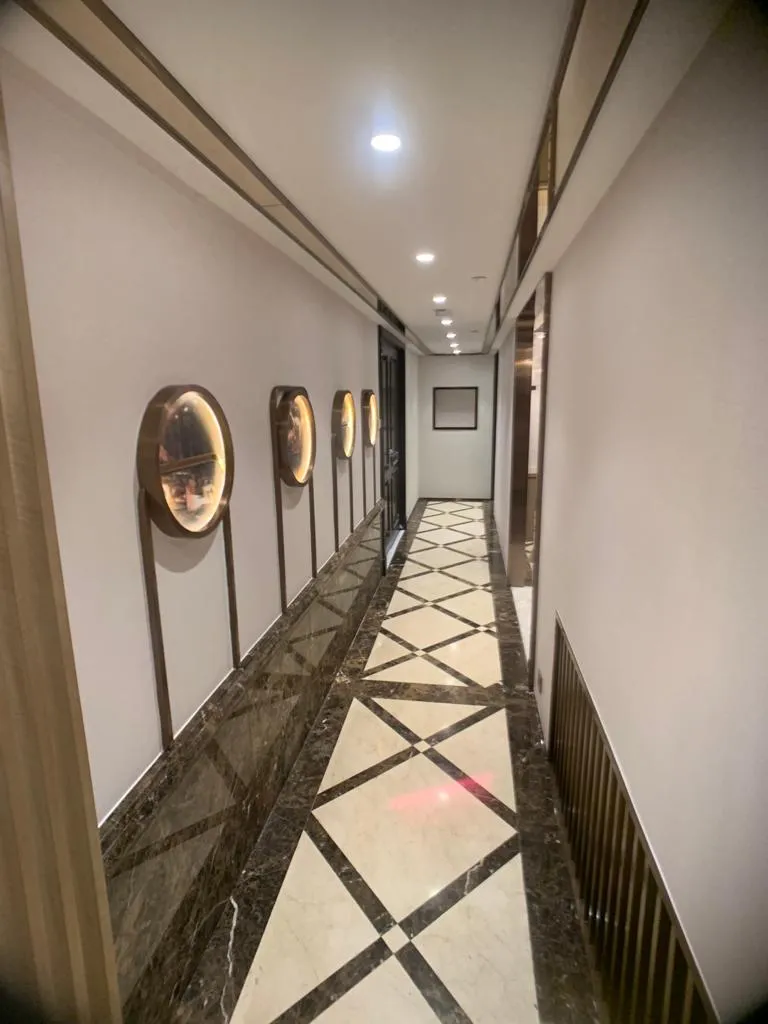Corridor with a round mirror feature and a marble diamond-pattern floor