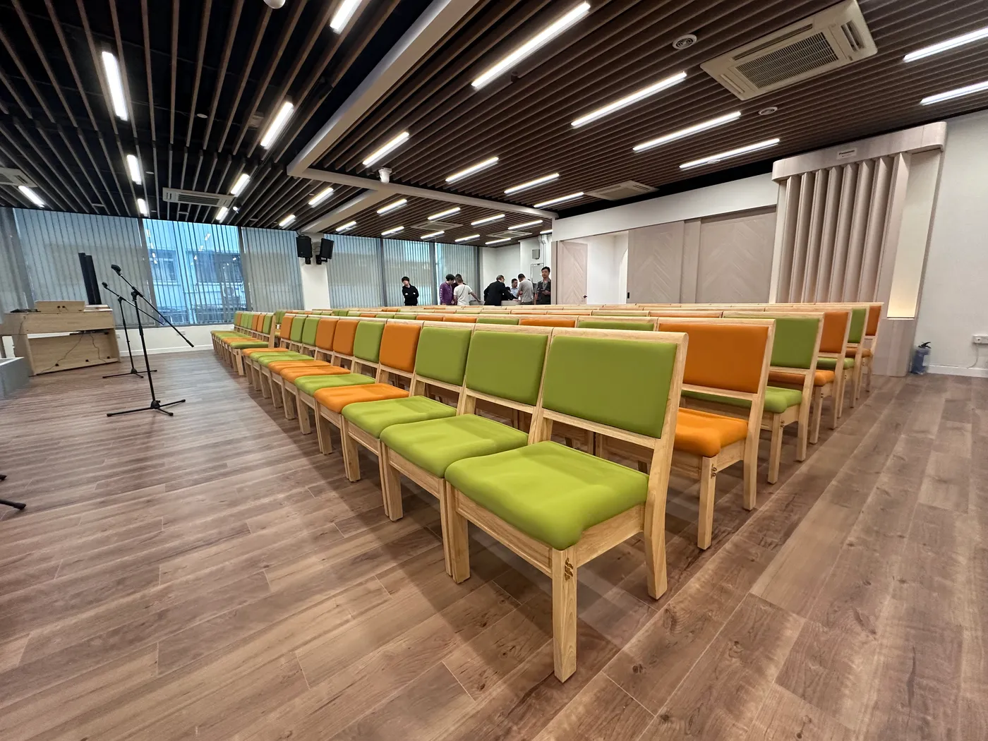 Assembly hall seating area with wood-framed green and orange upholstered chairs neatly arranged