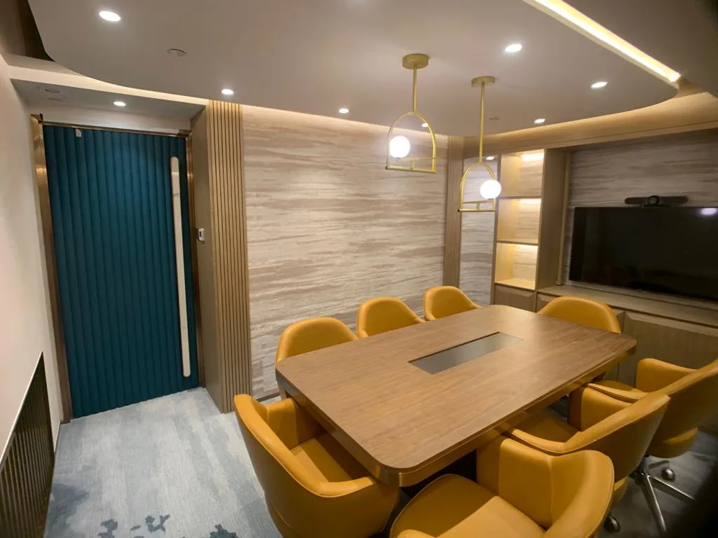 Meeting room with a long wood-grain table and mustard-yellow leather chairs