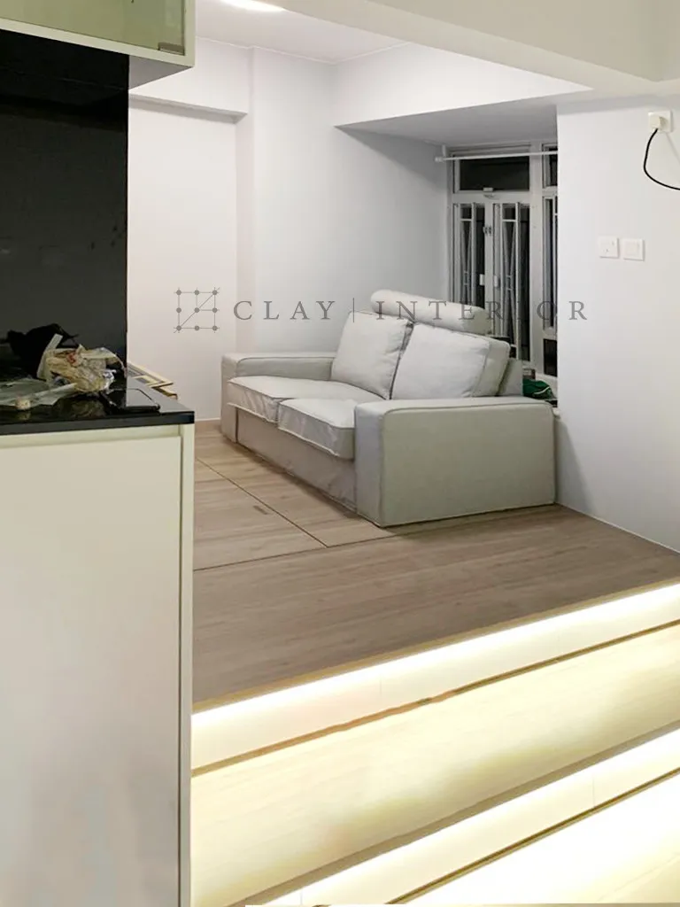 Living room raised timber platform with a light grey sofa and window-side seating