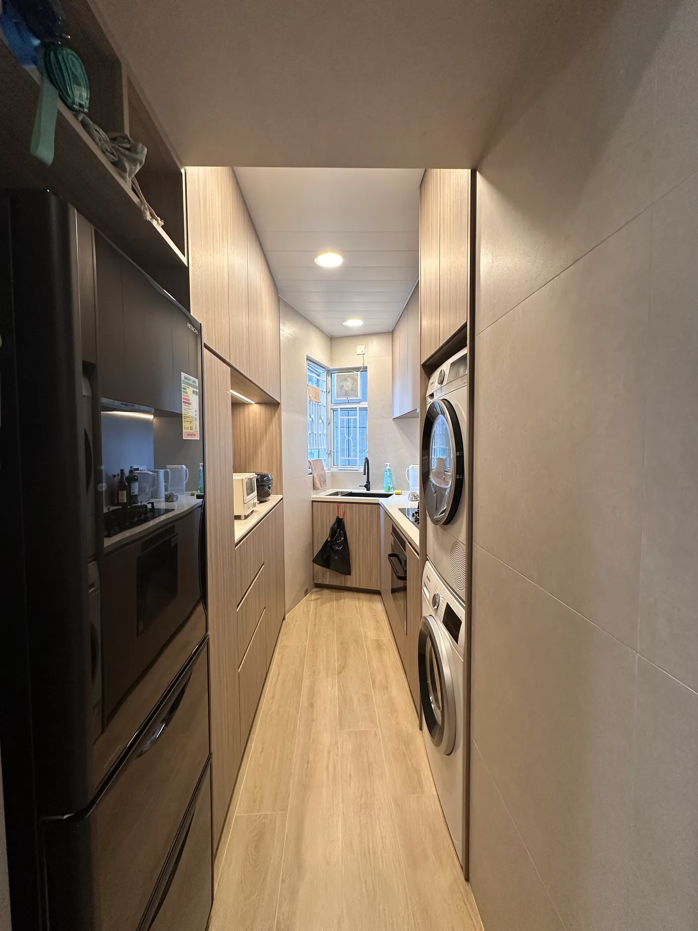 Open-plan kitchen overview with wood-grain cabinetry and a black glass countertop
