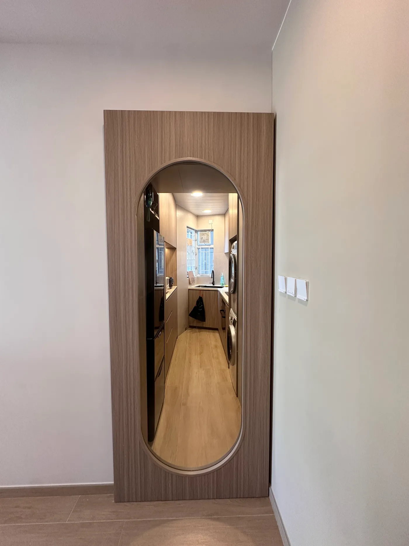 Wood-grain sliding door with an oval glass window, connecting the kitchen and living room